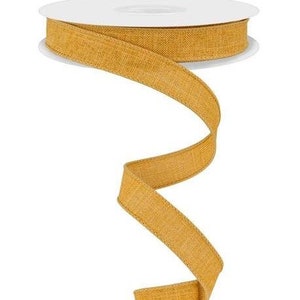 May include: A spool of mustard yellow linen ribbon with a textured weave. The ribbon is rolled up on a white spool.