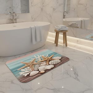May include: A rectangular bath mat featuring a beach scene with starfish, seashells, and coral. The mat has a blue, pink, and brown color scheme, creating a coastal theme. The mat is placed on a marble tile floor.