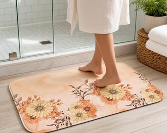 Tappetino da bagno con decorazioni floreali arancioni, fiori color pesca e crema, complemento d'arredo autunnale per il bagno.