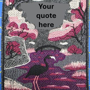Puede incluir: Parche bordado con un flamenco negro en un paisaje morado y rosa con un puente y árboles. El parche tiene el texto "Your quote here" en una burbuja gris. El parche está bordeado con hilo gris.