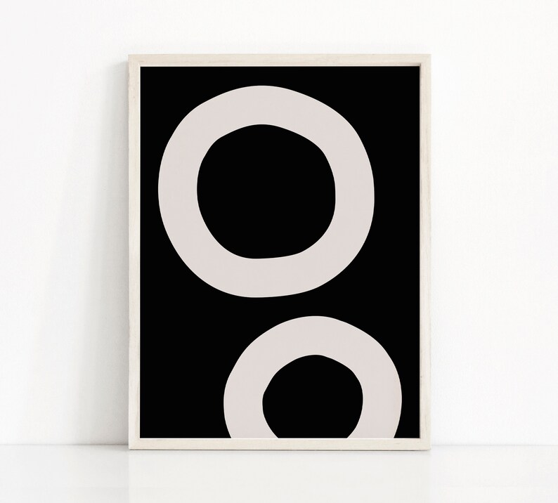 Puede incluir: Impresi&oacute;n de arte abstracto con dos c&iacute;rculos superpuestos en color gris claro sobre un fondo negro. La impresi&oacute;n est&aacute; enmarcada en un marco blanco.