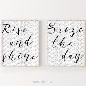 May include: Two black and white printable wall art prints with a white background and black polka dots. The first print says "Rise and shine" in a cursive font. The second print says "Seize the day" in a cursive font.