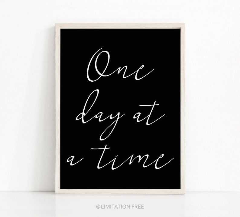 May include: Black and white printable wall art with the text "One day at a time" in a cursive font.