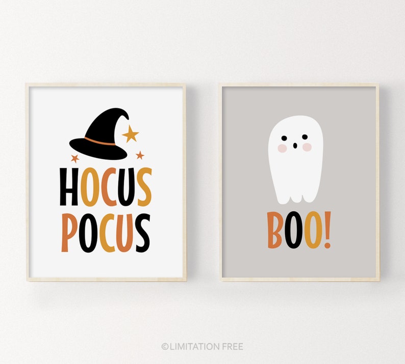 May include: Two framed Halloween-themed prints. One features a black witch hat, gold stars, and the words "Hocus Pocus" in black, gold, and orange. The other shows a white ghost with the word "Boo!" in orange.
