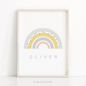 May include: A framed print with a rainbow design in shades of gray, yellow, and pink. The rainbow has black polka dots. The name "OLIVER" is printed below the rainbow.