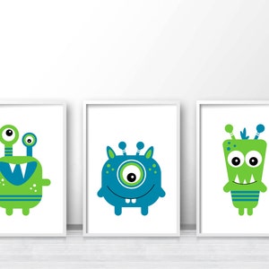 May include: Three framed prints featuring cartoon monsters with green and blue colors. The monsters have large eyes, teeth, and antennas.