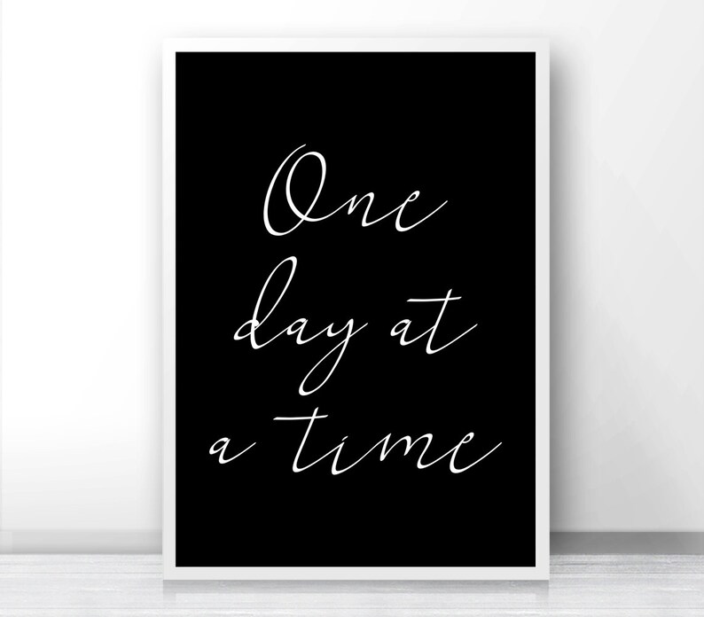 May include: Black and white printable wall art with the text "One day at a time" in a cursive font.