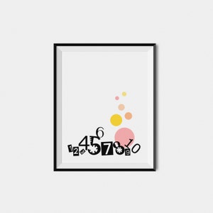 May include: A black framed print with a white background. The print features a cluster of black numbers, 1, 2, 3, 4, 5, 6, 7, 8, 9, 0, arranged in a random pattern. Above the numbers are three yellow and orange circles.