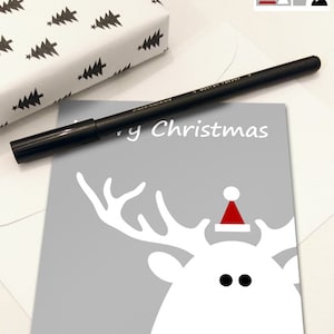 Peut inclure: Ensemble de deux cartes de Noël. Une carte représente un renne blanc avec un bonnet de Père Noël rouge sur fond gris. L'autre carte représente un sapin de Noël rouge et blanc avec une étoile au sommet sur fond blanc. Les deux cartes disent "Joyeux Noël" et "Bonne année".