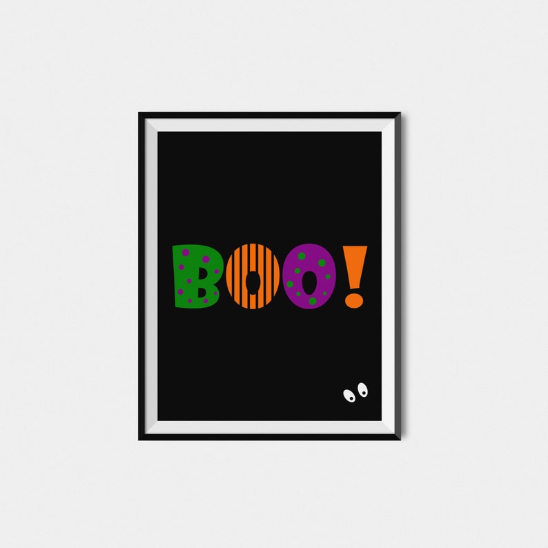 May include: A black framed print with the word "BOO!" in colorful letters. The letters are green, orange, purple, and orange. There are two white eyes on the bottom right corner of the print.