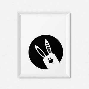 May include: Black and white illustration of a rabbit's head peeking out from a black circle.