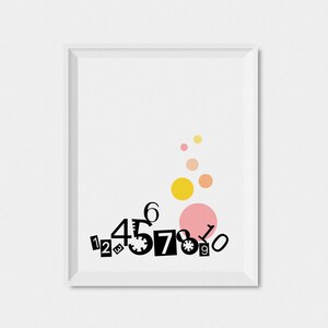 May include: A white framed print with black numbers 1 through 10 arranged in a cluster at the bottom. The numbers are in different sizes and styles. There are five yellow and pink circles in the upper half of the print.