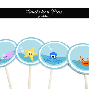 Pode incluir: Quatro toppers redondos azuis e brancos para cupcakes com diferentes criaturas marinhas. Os toppers representam uma estrela do mar, um polvo, um caranguejo e dois peixes.