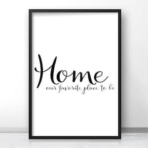 May include: A framed print with the word "Home" in a stylish script font, with the phrase "our favorite place to be" below it. The text is black on a white background, framed in black.