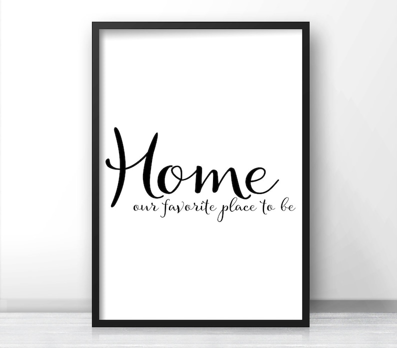 May include: A framed print with the word "Home" in a stylish script font, with the phrase "our favorite place to be" below it. The text is black on a white background, framed in black.