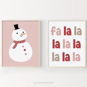 May include: Two printable Christmas art prints. The first print features a white snowman with a red and white striped scarf on a pink background. The second print features the text "fa la la la la la la la" in red, pink, and brown on a white background.