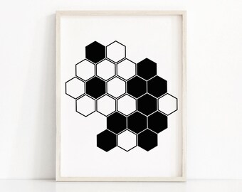 May include: A framed print featuring a black and white geometric design. The artwork showcases a pattern of interconnected hexagons, some filled in black and others left white. The print is set against a white background and framed in a light wood.