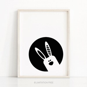May include: Black and white illustration of a rabbit's head peeking out from behind a black circle.