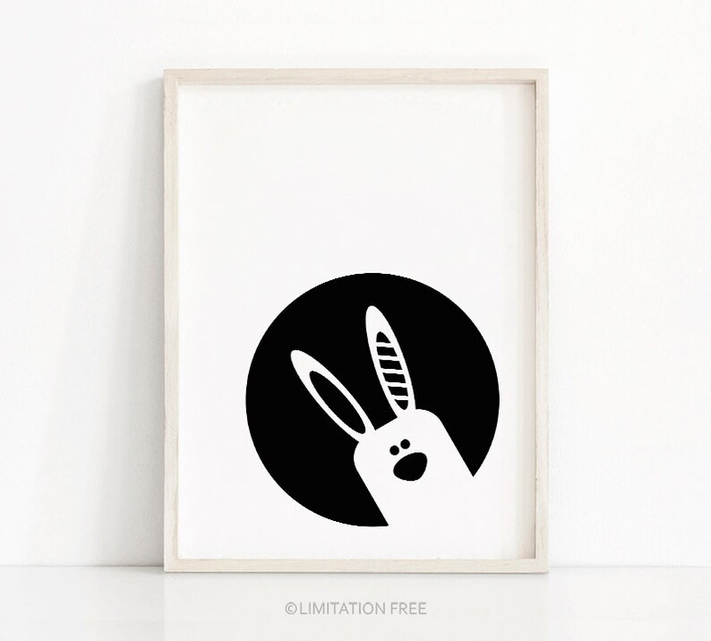 May include: Black and white illustration of a rabbit's head peeking out from behind a black circle.