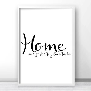May include: A framed white print with the word "Home" in a stylish black script font. Below, the phrase "our favorite place to be" is written in a smaller, cursive font. The print is displayed against a white background.