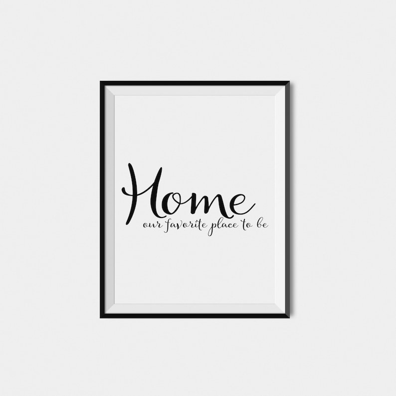May include: A framed print with the word "Home" in elegant black script, with the phrase "our favorite place to be" below it. The print is set against a white background, framed in a black border, suitable for home decor.