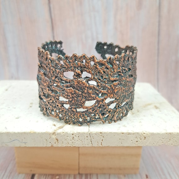 Real lace fabric electroformed in copper — the delicate textile pattern is permanently preserved in metal, creating a cuff that looks impossible.