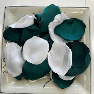 Op de afbeelding: Een witte keramische plaat gevuld met groene en witte stoffen bloemblaadjes. De bloemblaadjes zijn in een willekeurig patroon gerangschikt.