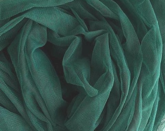 May include: Close-up of a dark teal fabric with a fine mesh texture. The fabric is gathered and folded, creating soft waves and shadows. The colour is a deep, rich shade of green.