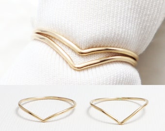 May include: Two gold-coloured, thin, v-shaped rings. The rings are stacked on top of each other.