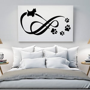 May include: Black and white silhouette of a dog with paw prints forming an infinity symbol on a white background. The image is displayed on a canvas and hung above a bed with white bedding.