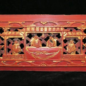 Puede incluir: Un panel de madera rojo con un diseño tallado de un pabellón chino con figuras en oro y rojo. El panel está decorado con detalles intrincados y es un hermoso ejemplo de la artesanía tradicional china.