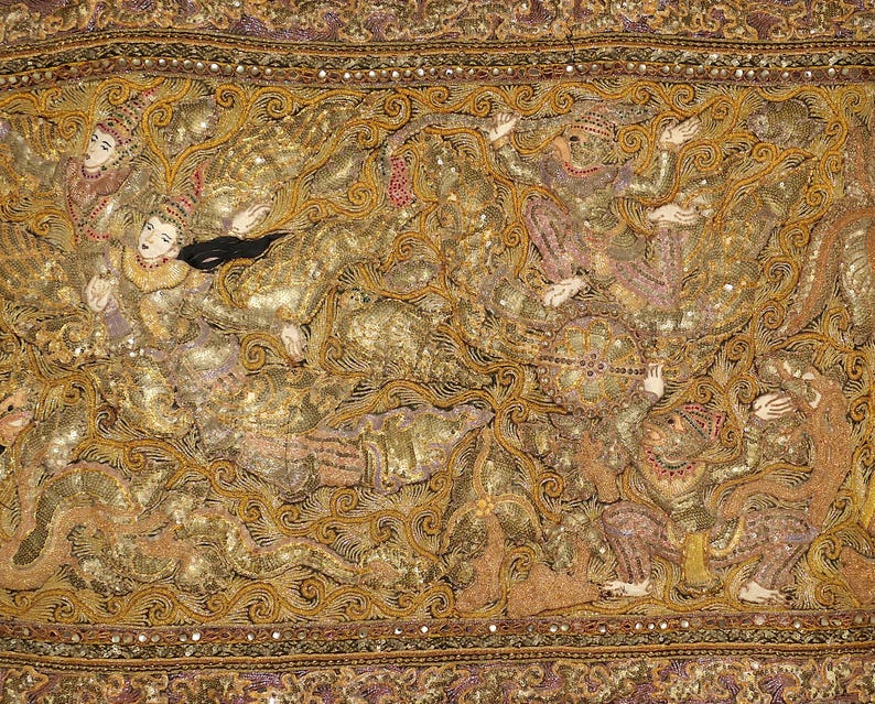May include: An ornate textile featuring a detailed, golden design with figures in traditional attire. The artwork incorporates intricate patterns, sequins, and a variety of colors, including gold, brown, and purple. The overall theme suggests a cultural or historical narrative.