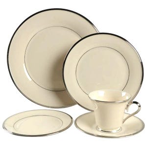 May include: A cream-colored fine china set with silver trim. The set includes a dinner plate, salad plate, saucer, and teacup. The plates and cup have a simple, elegant design, perfect for formal dining.