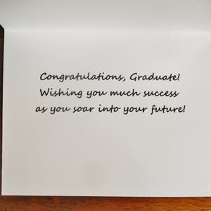 May include: A white card with a handwritten message that reads "Congratulations, Graduate! Wishing you much success as you soar into your future!"