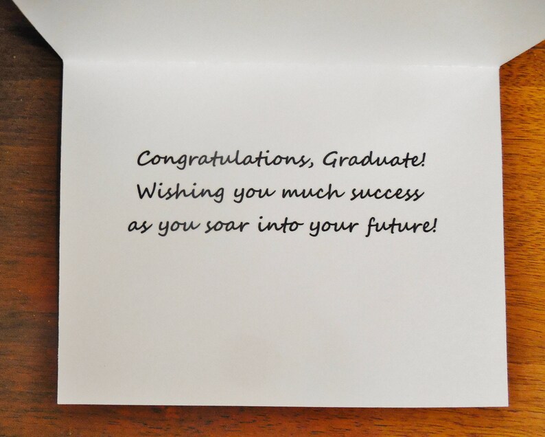 May include: A white card with a handwritten message that reads "Congratulations, Graduate! Wishing you much success as you soar into your future!"