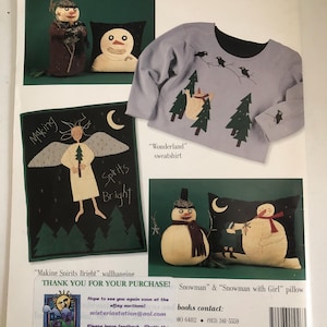May include: A page featuring winter-themed crafts. It includes a gray sweatshirt with a black collar and a design of trees and birds. There are also snowman pillows and a wall hanging with an angel and the words "Making Spirits Bright."