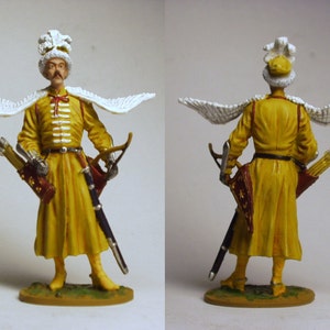 May include: A hand-painted miniature figurine of a soldier wearing a yellow tunic, white feathered hat, and white wings. The soldier is holding a bow and arrow and a sword.