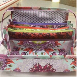 May include: A set of five fabric pouches with floral patterns and zippers. The pouches are nested inside each other, with the largest pouch at the bottom and the smallest pouch at the top. The pouches are made of a soft, colorful fabric with a variety of floral designs.