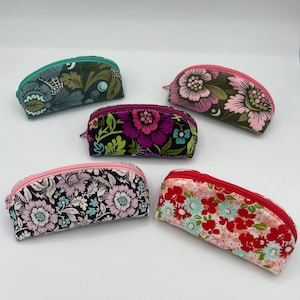 May include: Five small, half-circle zippered pouches with floral patterns. The pouches are in various colors, including pink, green, red, and purple.