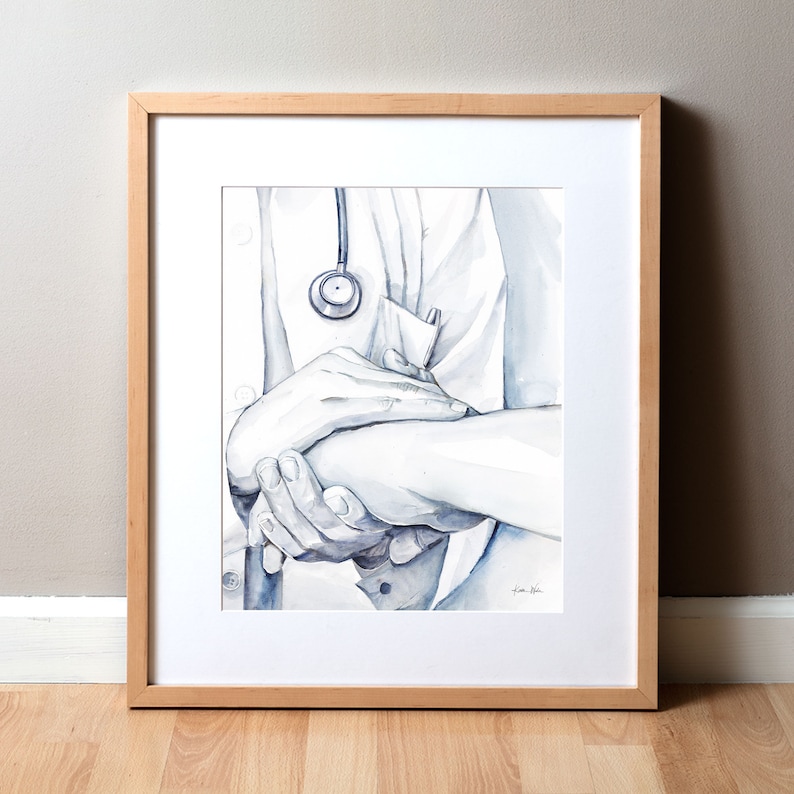 Op de afbeelding: Waterverfprint van de handen van een arts die de arm van een pati&euml;nt vasthoudt, met een stethoscoop. Het kunstwerk is ingelijst in een licht houten frame en heeft een grijstintenpalet. De afbeelding roept een gevoel van zorg en mededogen op.