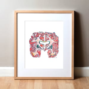 May include: A watercolor painting of a human brain in a light wood frame. The brain is depicted in shades of pink, red, and yellow with blue and green details. The painting is on a white background.