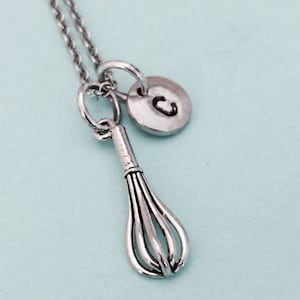 May include: Silver necklace with a charm of a whisk and a silver disc with the letter C.