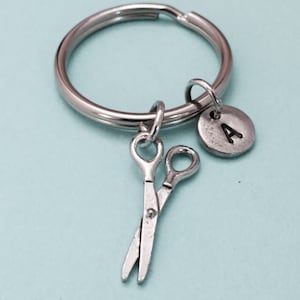 May include: Silver keychain with a silver letter A charm and a pair of silver scissors charm.