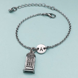 May include: A silver chain bracelet with a silver charm of a London telephone booth and a silver charm with the letter A.