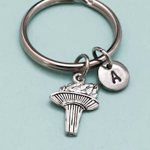 May include: Silver keychain with a torch charm and a silver disc charm with the letter A engraved on it.