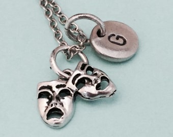 Puede incluir: Collar de plata con un dije de dos máscaras de teatro y un dije de plata con la letra G.