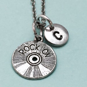 May include: Silver necklace with a charm that says "Rock On" and a charm with the letter "C".