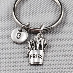 May include: Silver keychain with a letter G charm and a charm of a small bucket of fries with the word "FRIES" on it.