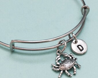 May include: A silver charm bracelet with a crab charm and a silver charm with the letter D.