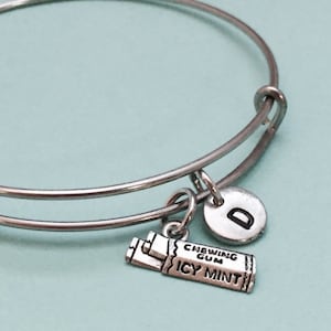 May include: A silver charm bracelet with a charm that says "Chewing Gum Icy Mint" and a silver charm with the letter "D".